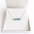 Aura aus 925 Silber mit drei blauen Aquamarinen in einer hellen Schmuckbox, als Beispiel für das Design.