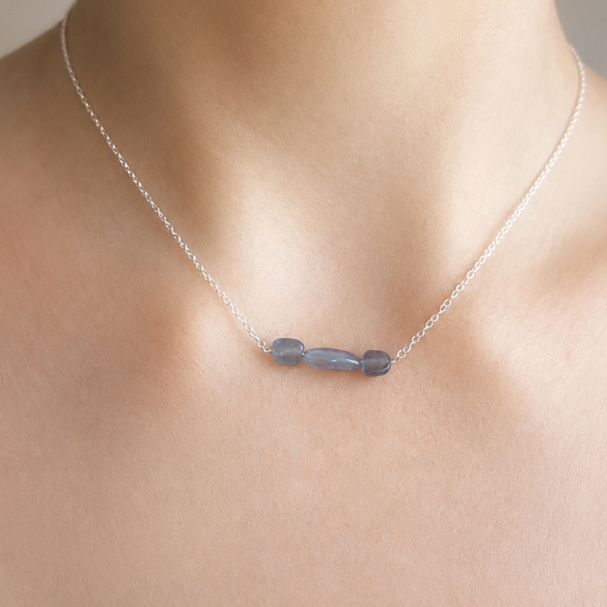 Aura aus 925 Silber mit drei blauen Aquamarinen, am Hals getragen als Beispiel für das Design.
